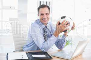Smiling businessman looking at camera with foot ball
