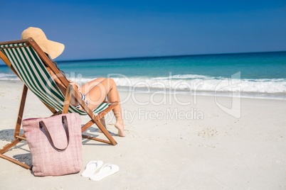 Side view of pretty brunette relaxing on deck chair at the beach