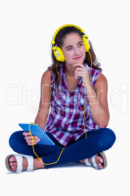 Thoughtful pretty brunette listening music with her tablet compu