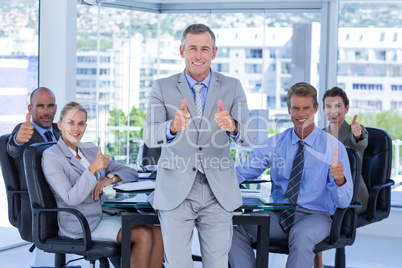 Business team smiling at camera showing thumbs up