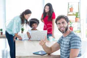 Casual businessman using digital tablet with colleagues behind i