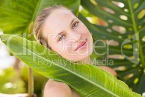 Beautiful blonde smiling at camera behind leaf