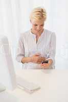 Smiling blonde woman using computer and mobile