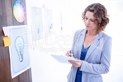 Creative businesswoman taking note on clipboard