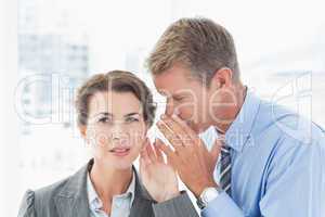 Businessman whispering something to his colleague