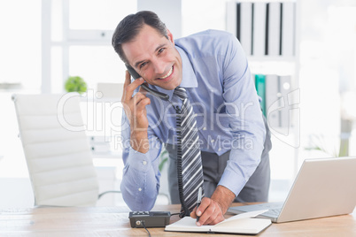 Smiling businessman phoning at his desk