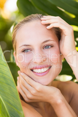 Beautiful blonde smiling at camera behind leaf