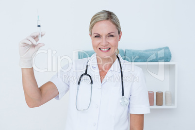 Smiling doctor showing syringe to camera