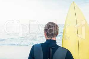 Man in wetsuit with a surfboard on a sunny day