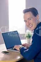 Happy businessman with his laptop smiling at camera