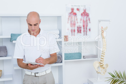 Doctor writing on clipboard