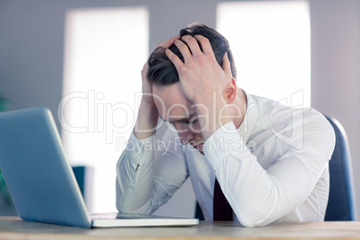 Worried businessman with head in hands