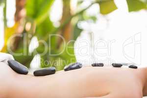 Beautiful woman receiving stone massage at spa center