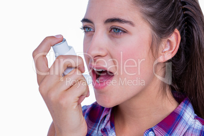 Pretty brunette woman using asthma inhaler