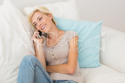 Smiling blonde woman phoning on the sofa