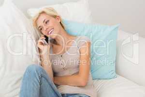 Smiling blonde woman phoning on the sofa