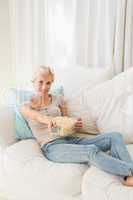 Portrait smiling blonde woman watching TV and eating pop corn