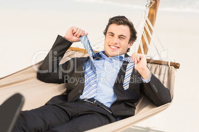 Businessman removing his tie on the hammock