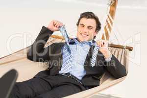 Businessman removing his tie on the hammock