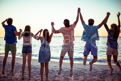 Happy friends holding hands and jumping