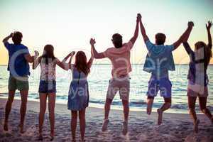 Happy friends holding hands and jumping