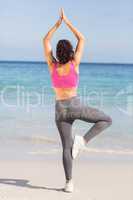 Beautiful fit woman doing yoga beside the sea