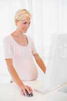 Smiling of a blonde pregnant using computer
