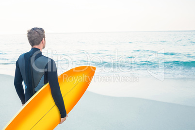 Man in wetsuit with a surfboard on a sunny day