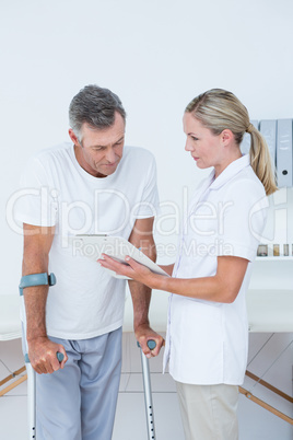 Doctor showing clipboard to her patient with crutch