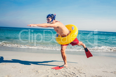 Man wearing flippers and rubber ring at the beach