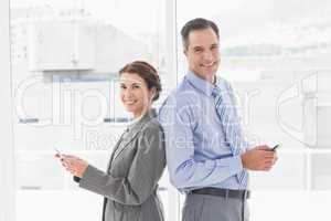 Smiling businesswoman back-to-back with colleague