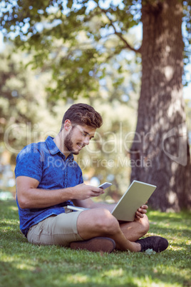 Hipster using laptop and phone in the park