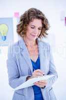 Creative businesswoman taking note on clipboard