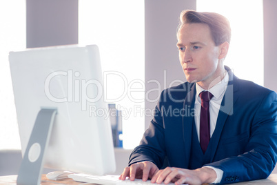 Serious businessman typing on computer