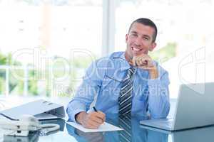 Smiling businessman writing notes