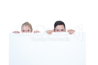 Young couple hiding behind a blank sign Young couple hiding behind a blank sign