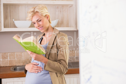 Smiling blonde pregnancy reading a book