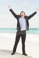 Happy businessman cheering at the beach