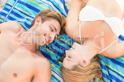 smiling couple lying on a towel looking at camera