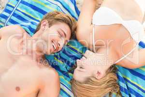 smiling couple lying on a towel looking at camera