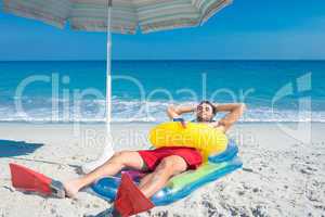Man lying on the beach with flippers and rubber ring