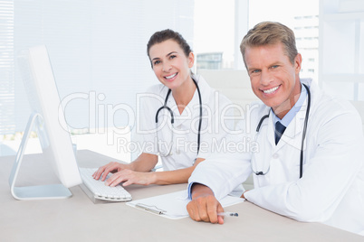 Smiling female and male doctors looking at camera