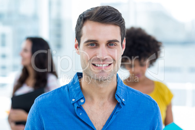 Smiling businessman with his colleagues behind