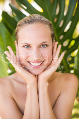 Beautiful blonde smiling at camera behind leaf