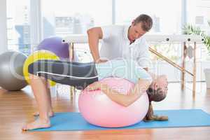 Trainer working with woman on exercise ball