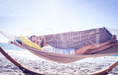 Pretty brunette relaxing with her straw hat in the hammock