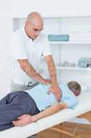 Physiotherapist doing back massage to his patient