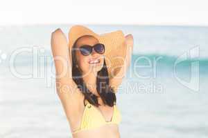 Brunette relaxing with a straw hat smiling at camera