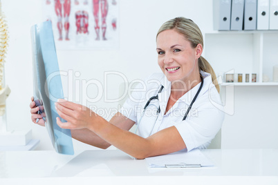 Smiling doctor looking at camera and holding X-Rays