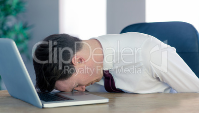 Exhausted businessman sleeping head on laptop